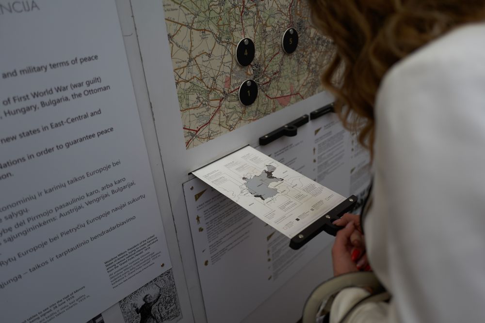 A woman faces the internal wall of the After the Great War exhibition. She inspects one of the pull-out infographic panels, which depicts the territorial losses of Germany after the First World War.