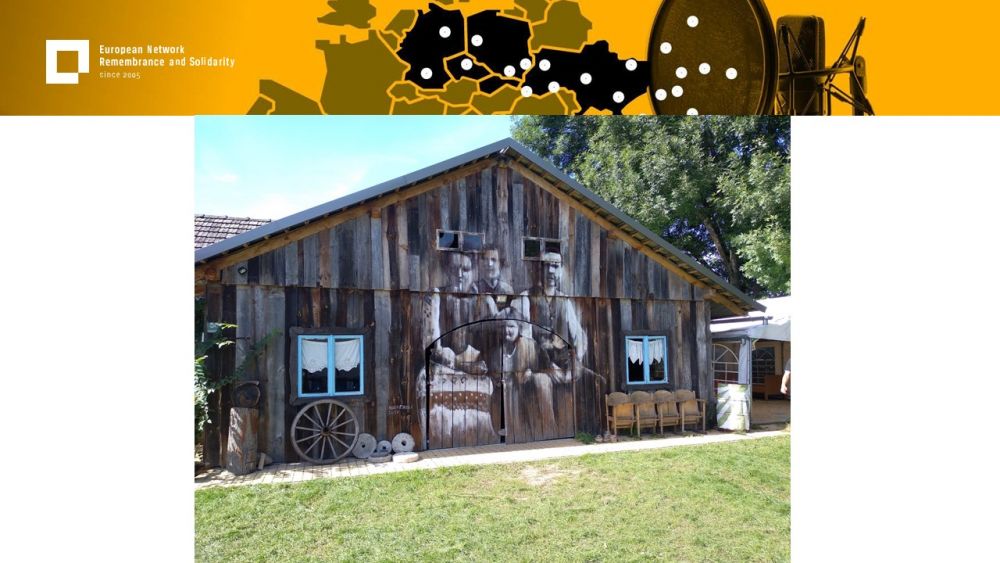 Presentation slide with a single photo in the center. It presents a wooden country house. On its dark facade, a large chalk painting depicting a sited family, reminiscent of the old photographs. Above all of it, a gold-yellow header with European Network remembrance and Solidarity.
