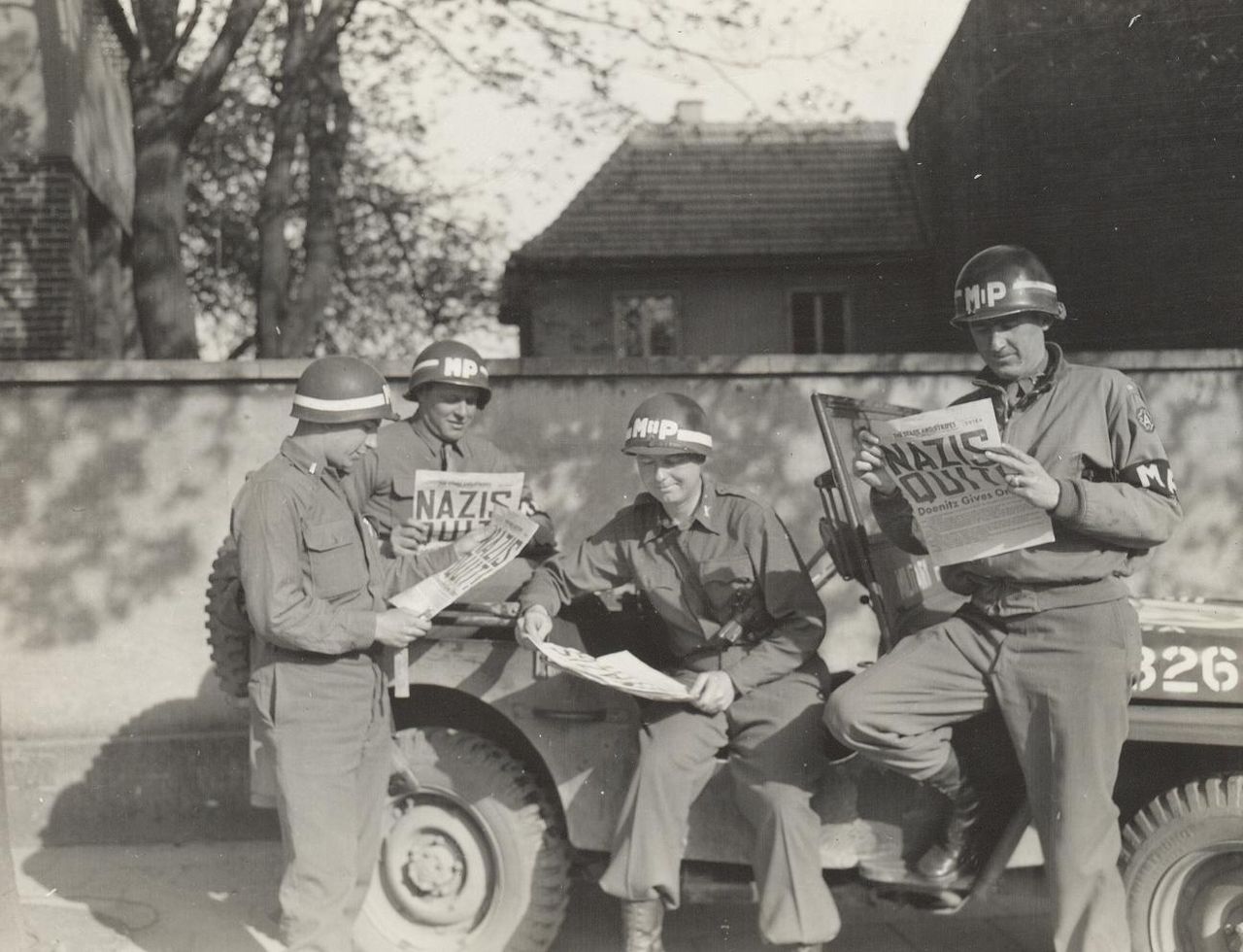 United States military policemen reading about the German surrender in the newspaper Stars and Stripes. Photo Courtesy of U.S. Army / Public Domain